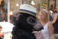 a man in a hat and animal costume on the street with people walking around him