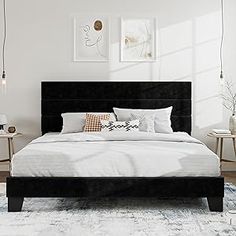 a bedroom with white walls and black bedding in the center, along with two side tables on either side