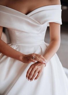 a woman in a white dress is holding her hands on her waist and wearing an engagement ring