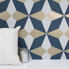 a white pillow sitting on top of a table next to a wall with geometric designs