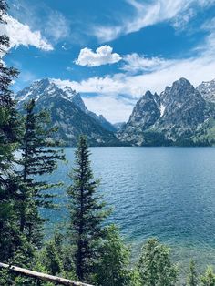 a lake surrounded by trees and mountains under a blue sky