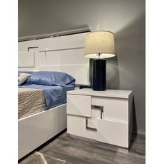 a white bed sitting next to a night stand with a lamp on top of it