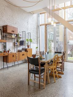 a dining room table surrounded by chairs and shelves