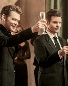 two men in suits are toasting with wine glasses