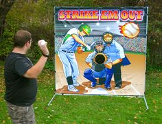 a man standing in front of a sign that says strike em out with baseball players on it