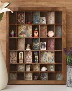 a vase with flowers in it sitting next to a wooden shelf filled with cards and knick knacks