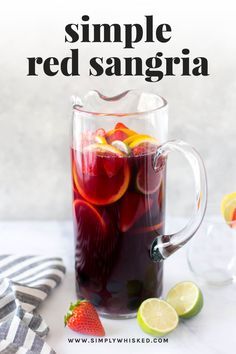 a pitcher filled with red sangria next to sliced lemons and strawberries