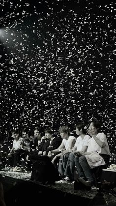 a group of people sitting on top of a stage with confetti falling in the air