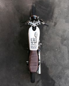 a white and brown motorcycle parked on top of a cement floor next to a wall