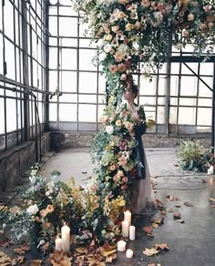 a bride and groom standing under an umbrella covered in flowers with candles on the ground