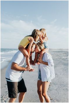 a group of people standing on top of each other at the beach near the ocean