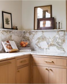 a kitchen with marble counter tops and wooden cabinetry in the corner, along with framed pictures on the wall