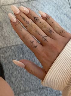 a woman's hand with stars and moon tattoos on it