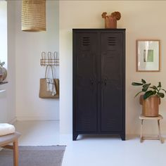 a black locker sitting in the corner of a room next to a potted plant