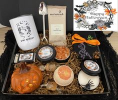 an assortment of halloween treats in a gift box with candles, candy and coffee mugs