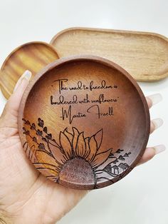 a hand holding a wooden plate with a sunflower on it and the words, the world is beautiful