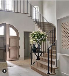 a large foyer with stairs and flowers on the table in front of it's door