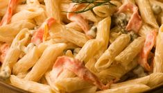 a pasta dish with meat and vegetables in a brown bowl on top of a wooden table