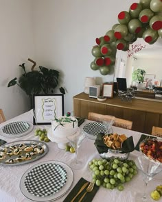 a table is set with plates, silverware and green grapes for a holiday party