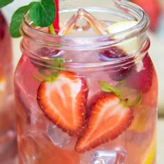 two mason jars filled with liquid and strawberries