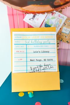 a yellow and blue sign sitting on top of a table next to confetti