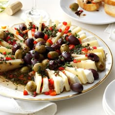 a platter filled with olives, cheese and bread on top of a table