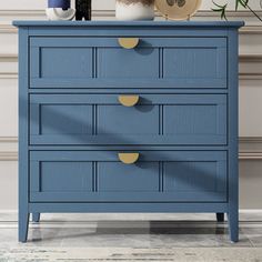 a blue chest of drawers with two vases on top