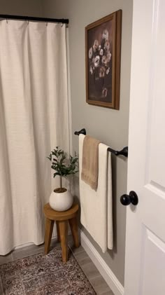 a white toilet sitting next to a wooden stool under a painting on the wall in a bathroom