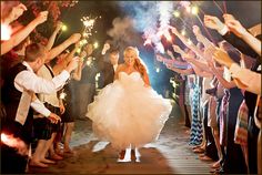 a bride and groom walk through sparklers at their wedding