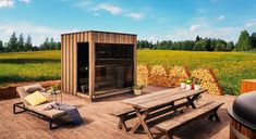 an outdoor hot tub and picnic table on a wooden deck with yellow flowers in the background