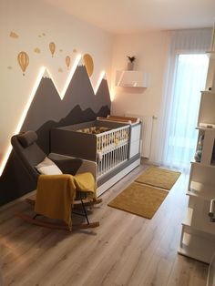 a baby's room with mountains and hot air balloons on the wall