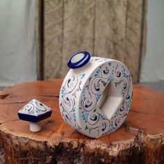 a white and blue vase sitting on top of a wooden table next to a piece of wood