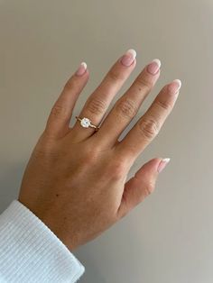 a woman's hand with white manicured nails and a diamond ring