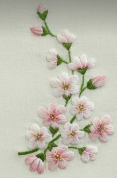 pink and white flowers are embroidered onto the side of a piece of cloth with green stems