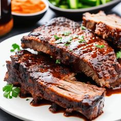 ribs covered in bbq sauce and garnished with parsley on a white plate