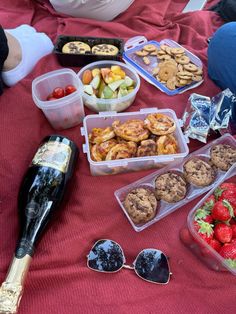 a table topped with lots of food and drinks on top of a red sheet covered ground