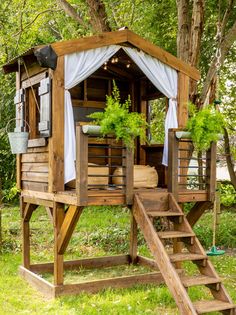 a tree house with stairs leading up to it and plants growing on the deck area