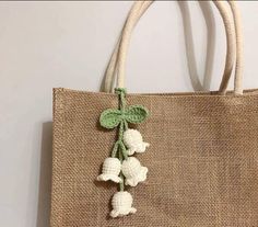 a jute bag with white flowers and green leaves hanging from the side on a wall