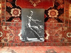 a black and white photo of a man on a dog in front of a rug