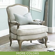 a white chair sitting on top of a wooden floor next to a mirror and rug