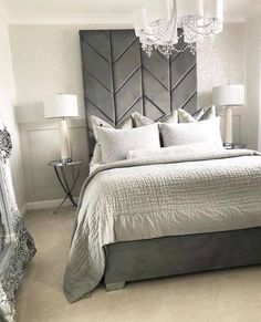 a bedroom with a large bed, chandelier and mirror in the corner on the wall