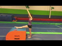 a woman standing on top of a blue and green trampoline in a gym