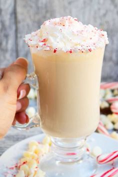 someone is holding a hot chocolate drink with marshmallows and candy canes