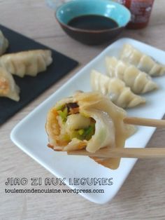 some dumplings are sitting on a plate with chopsticks