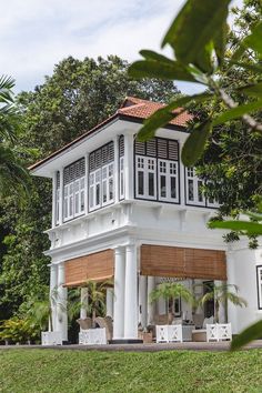 a large white house sitting in the middle of a lush green field with trees around it