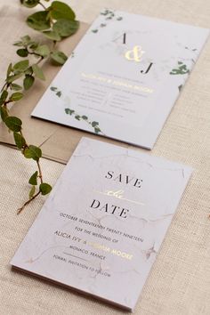 the wedding stationery is laid out with greenery