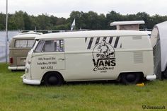 an old vw bus is parked in the grass next to another van and tent