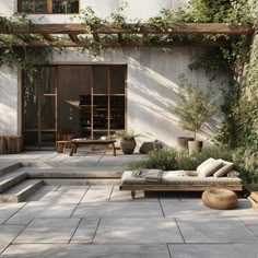 an outdoor seating area with stone steps and greenery on the side of a building