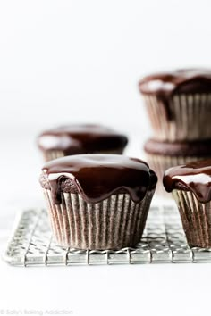 three chocolate cupcakes sitting on top of a cooling rack