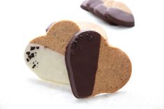 two heart shaped cookies with chocolate on top, one is white and the other is brown